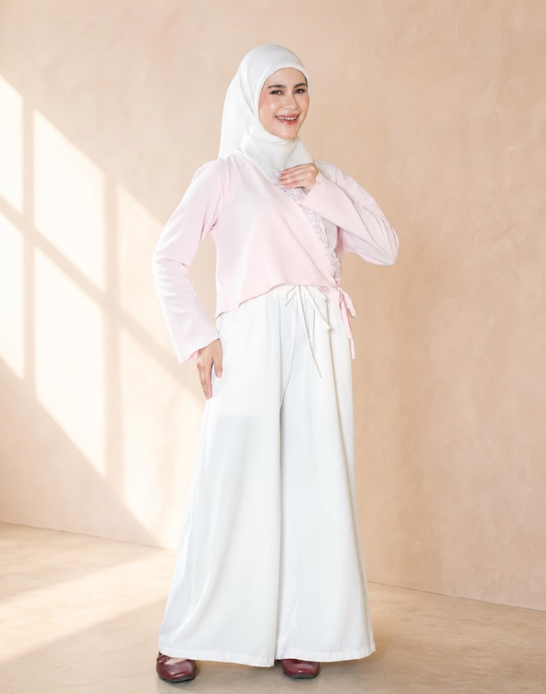 Model berhijab putih mengenakan lapisan merah muda dan celana putih