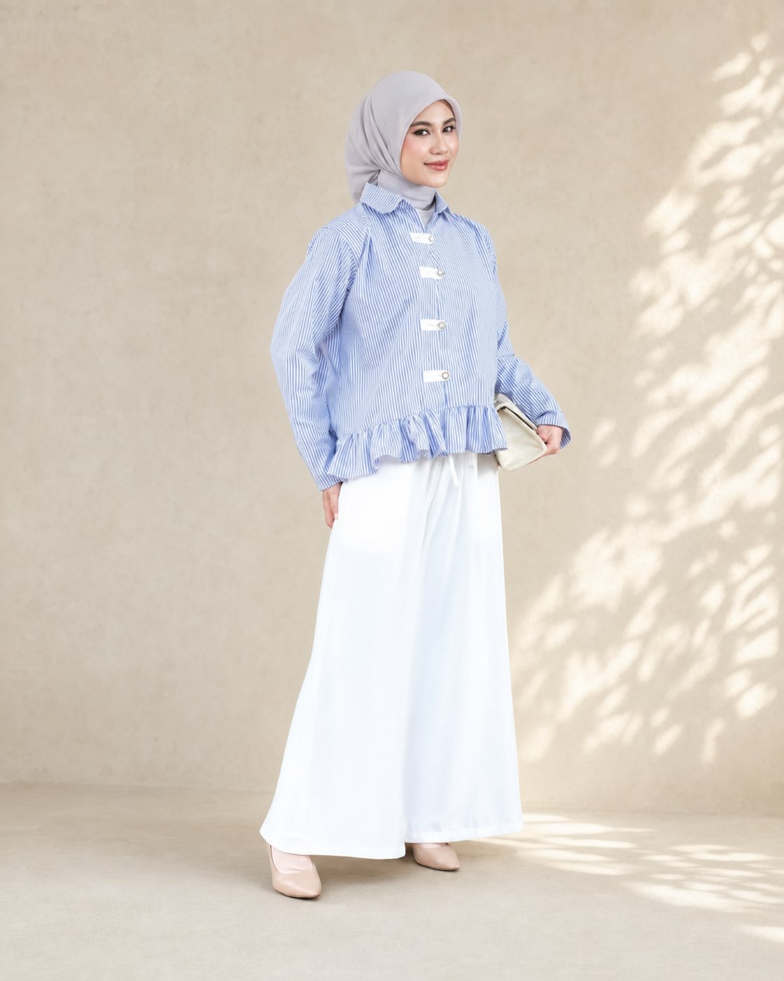 Model berhijab mengenakan atasan garis biru dan bawahan putih