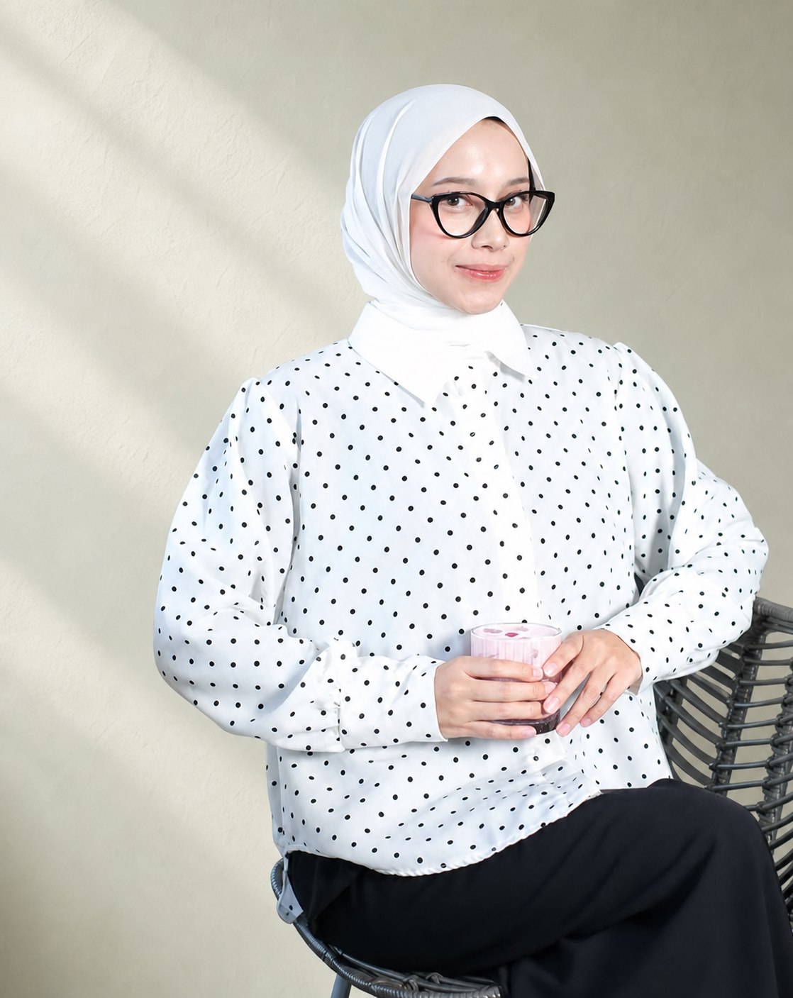 Model berhijab putih dan berkacamata mengenakan atasan polkadot