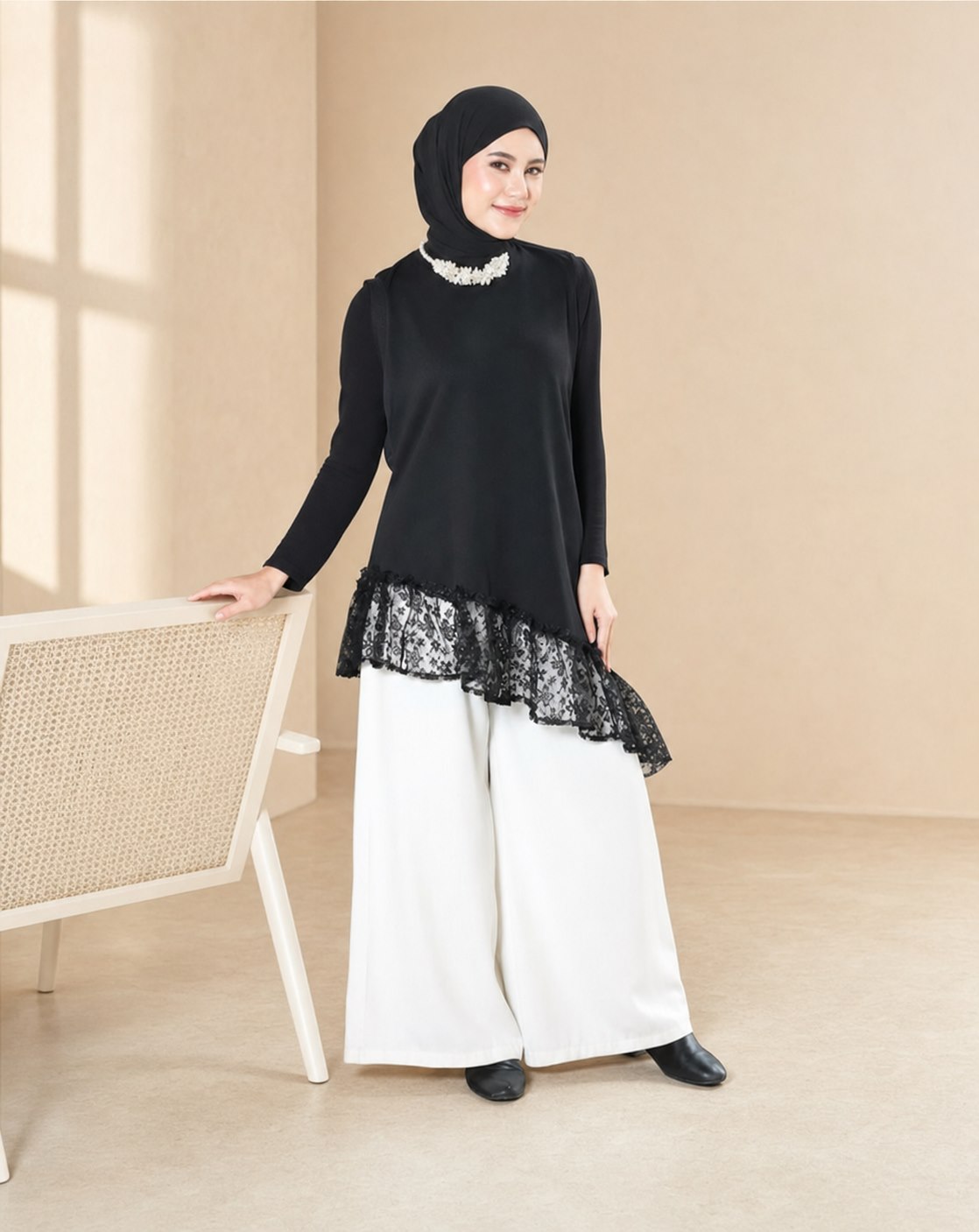 Model berhijab mengenakan tunik hitam beraksen renda